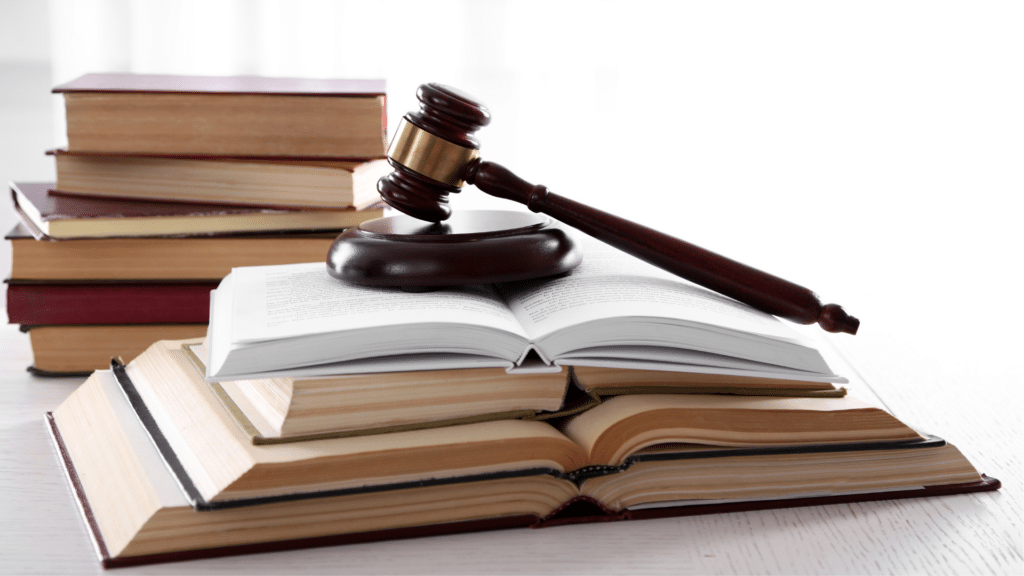 An image of open books stacked on a desk with a legal gavel.